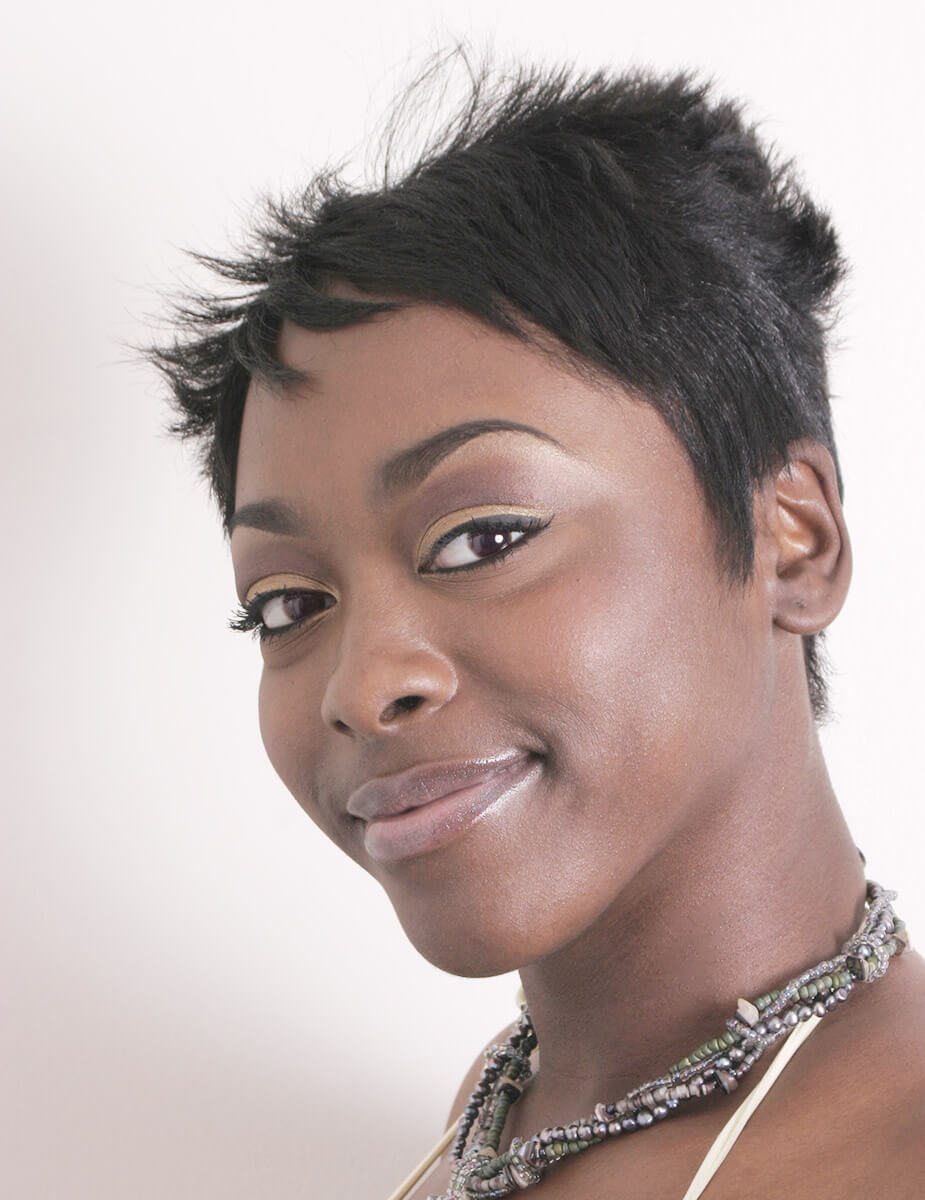 Close-up beauty portrait of a woman with short natural hair, soft skin tones, and clean studio makeup.