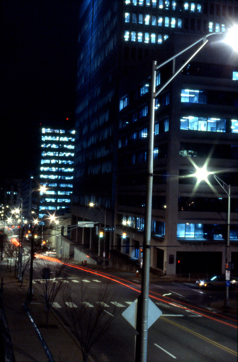 Long exposure night photograph of downtown Nashville with glowing office windows and light trails from passing cars.