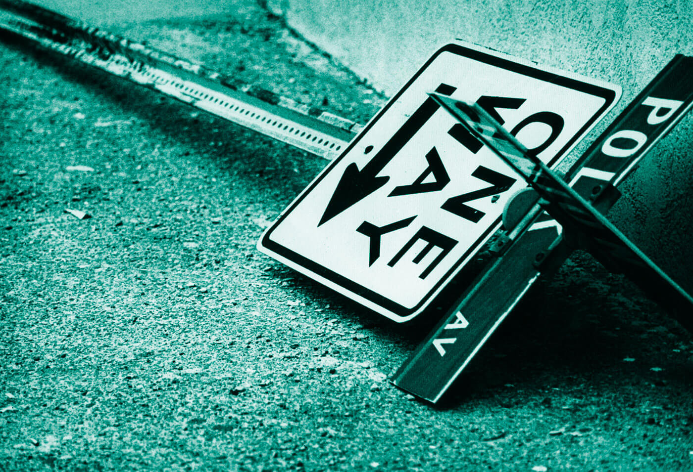 Tilted one-way street sign and metal post on gritty pavement, toned in teal for a graphic urban look.